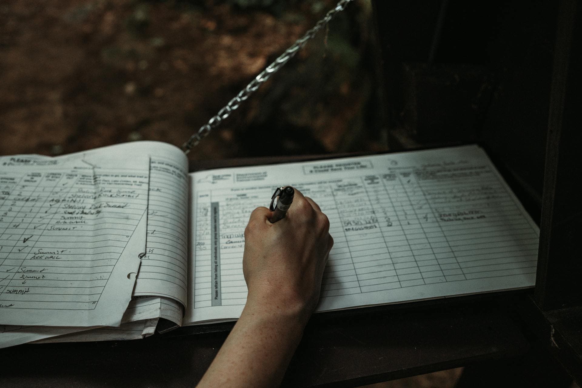 A hand filling in a paper logbook by hand