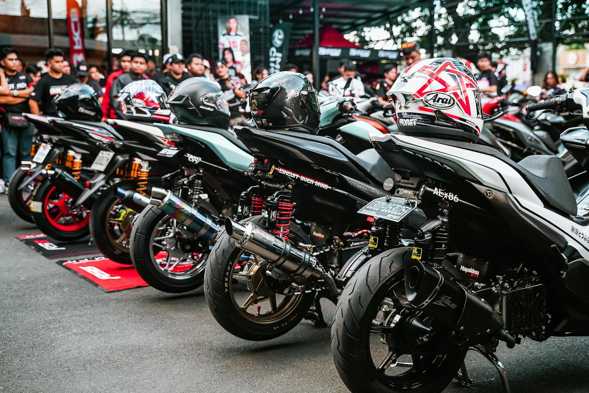 A row of customised scooters and motorcycles lined up at a shop event